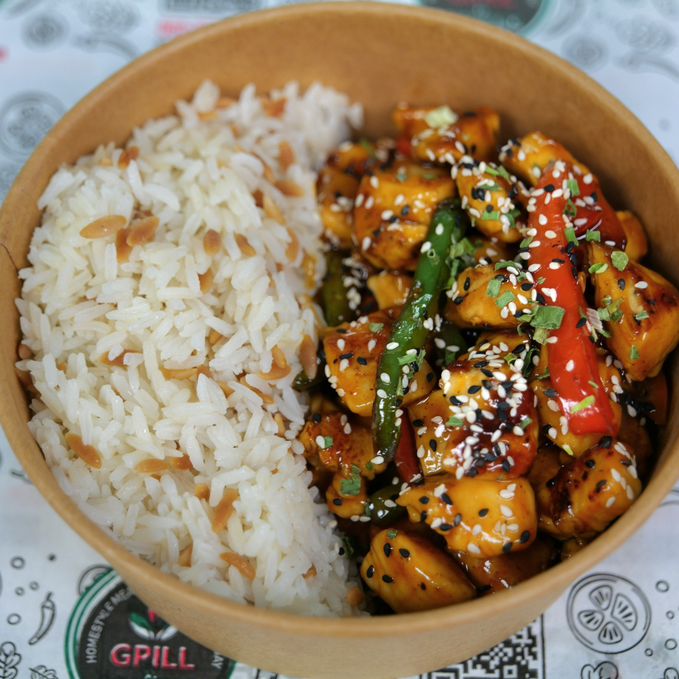 A close-up of a takeout bowl with white rice and sesame chicken with peppers and green beans.