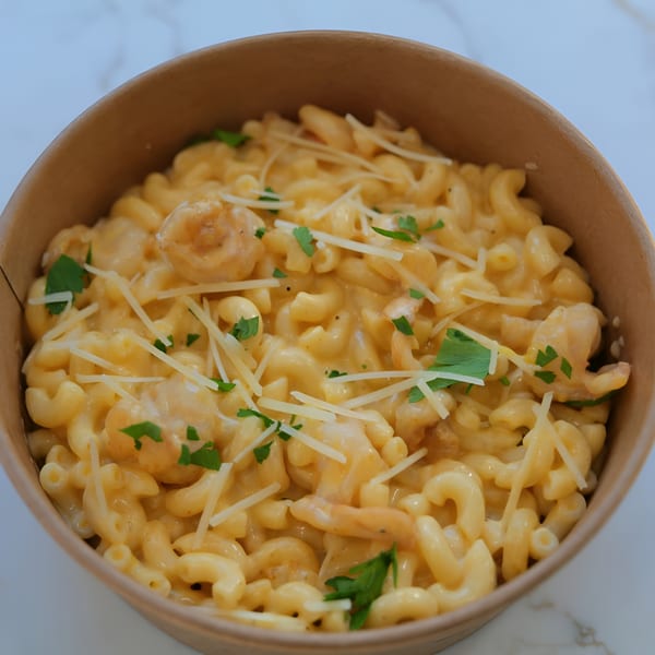 Creamy macaroni and cheese with shredded cheese and parsley in a brown bowl.