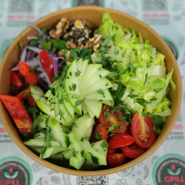 A vibrant salad in a bowl with lettuce, tomatoes, cucumbers, red onions, bell peppers, and walnuts.